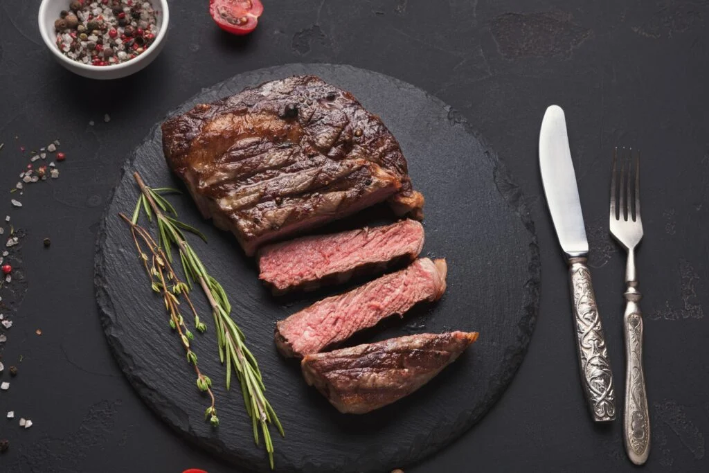 Sliced steak served on a dark board